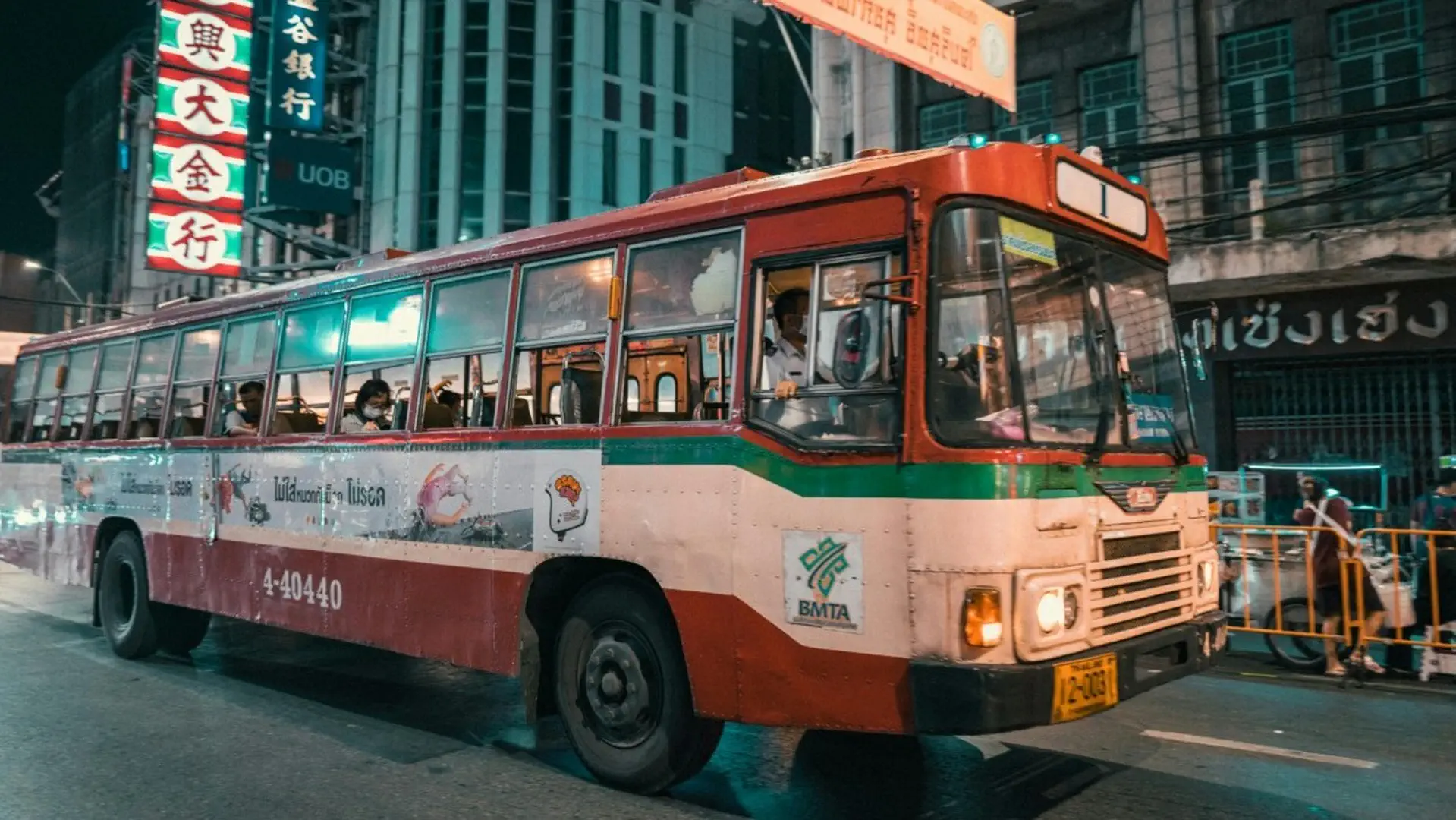 Czerwono-biały autobus BMTA na ulicach nocnego Bangkoku, popularny środek transportu publicznego